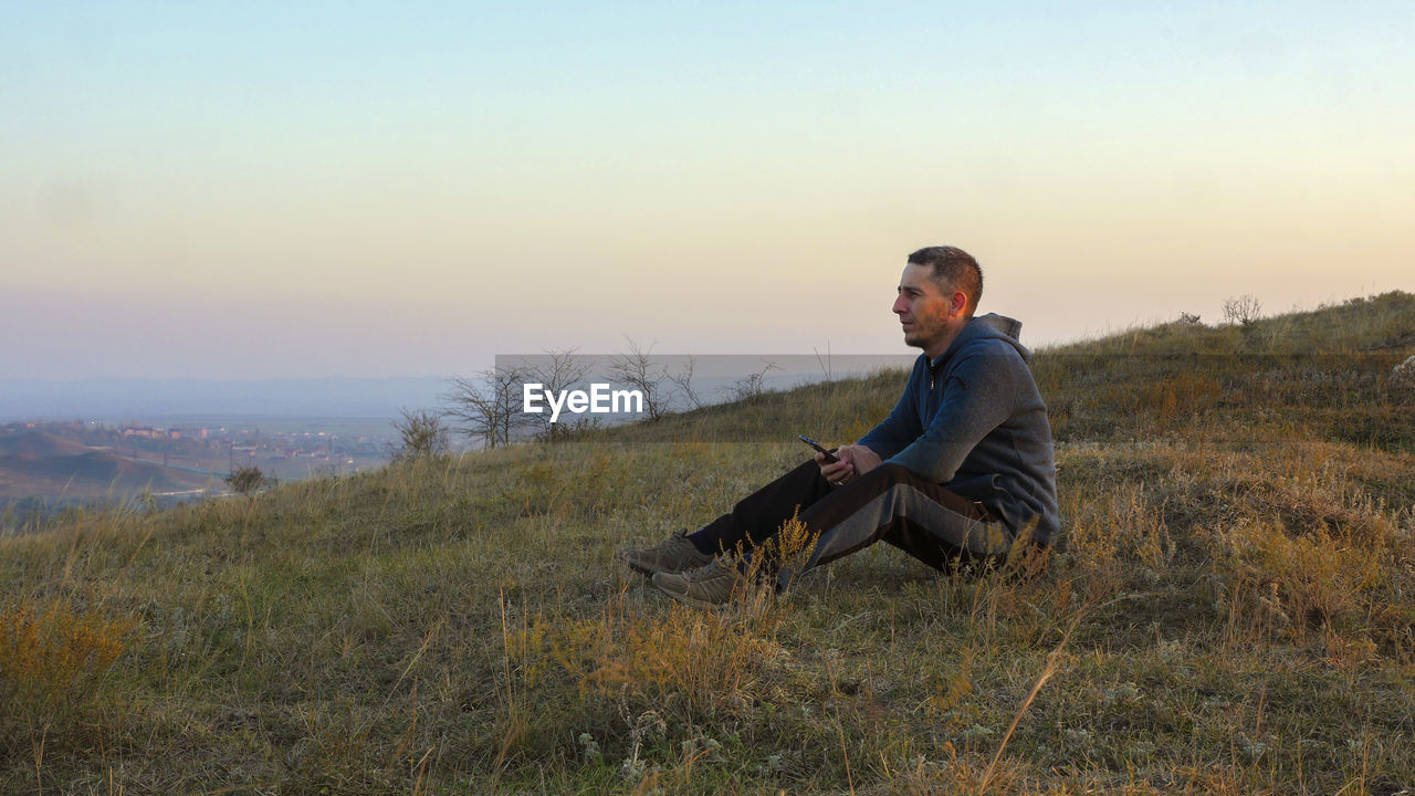 Man sitting on mountain during sunset