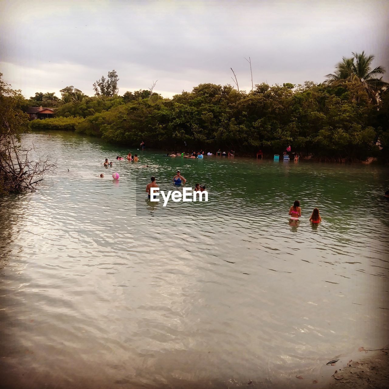 PEOPLE FLOATING ON LAKE AGAINST TREES