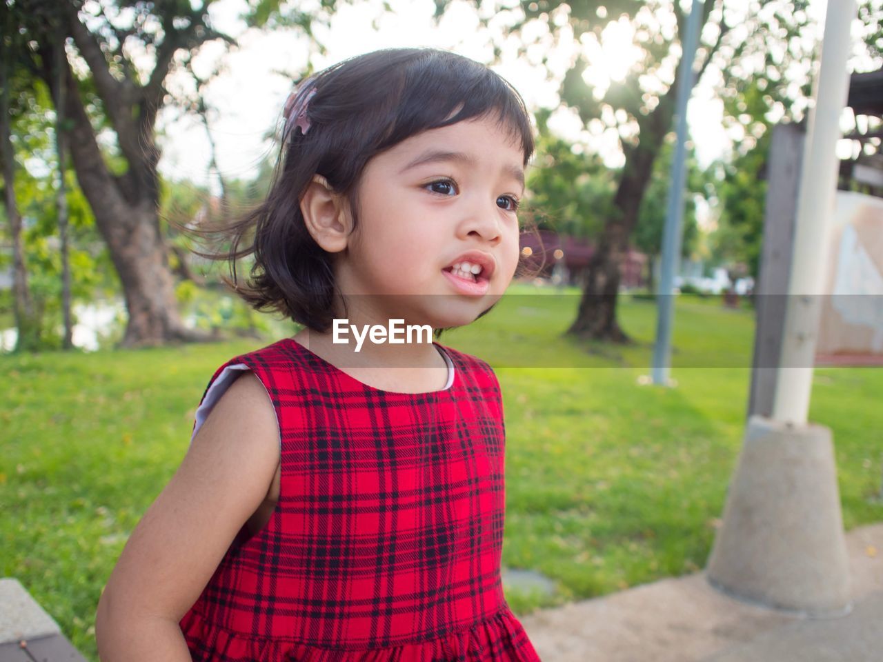 Cute smiling girl looking away while standing at park