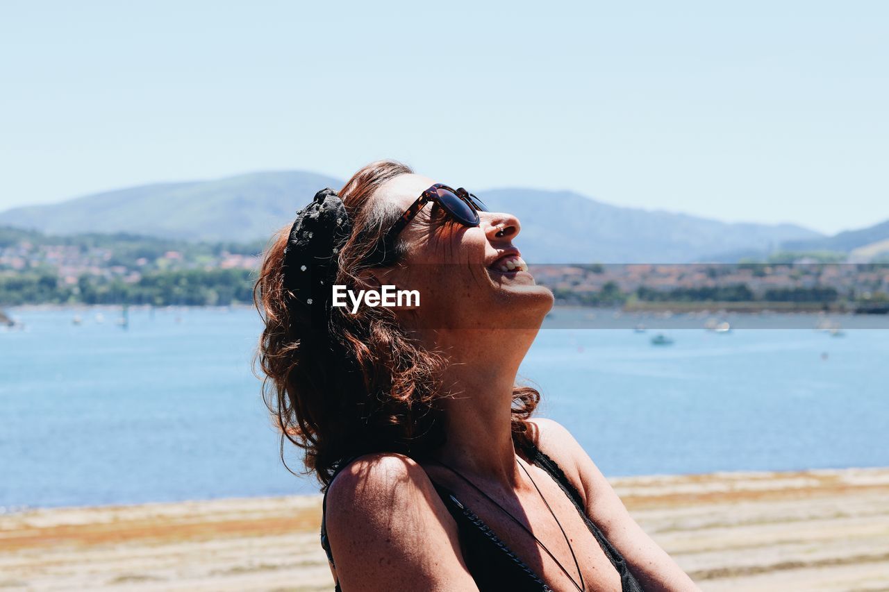 Mid adult woman looking at sea against sky