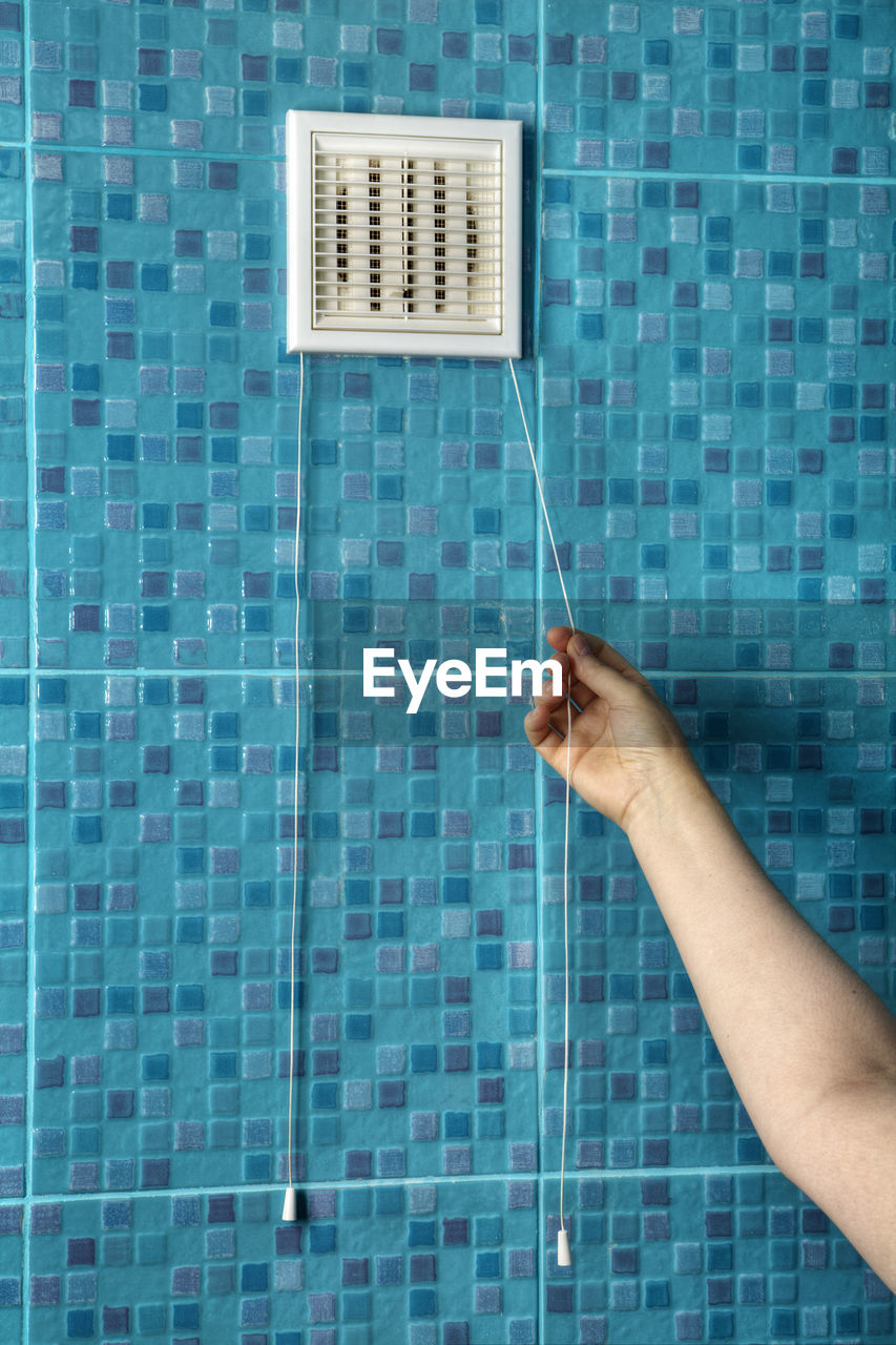 Cropped hand of man checking air duct at bathroom