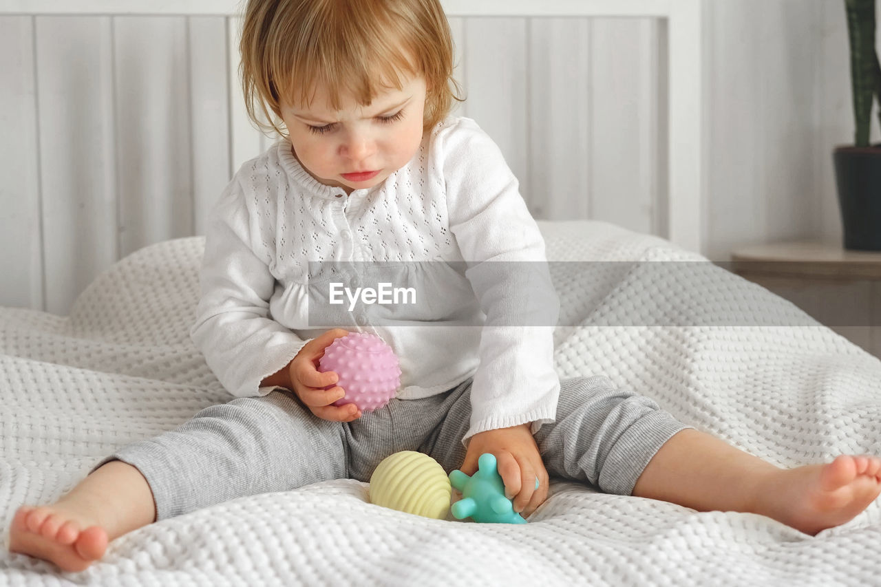 Baby girl playing tactile knobby balls. young child hand plays sensory massage ball