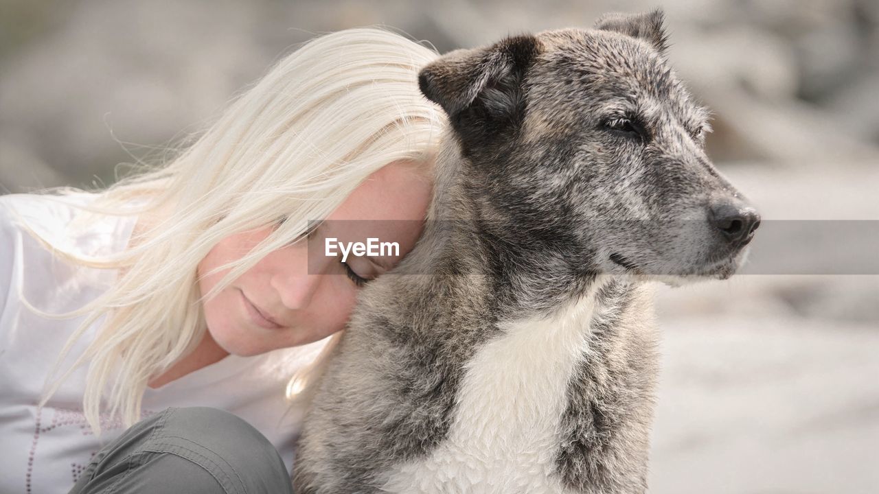 Close-up of young woman leaning on dog