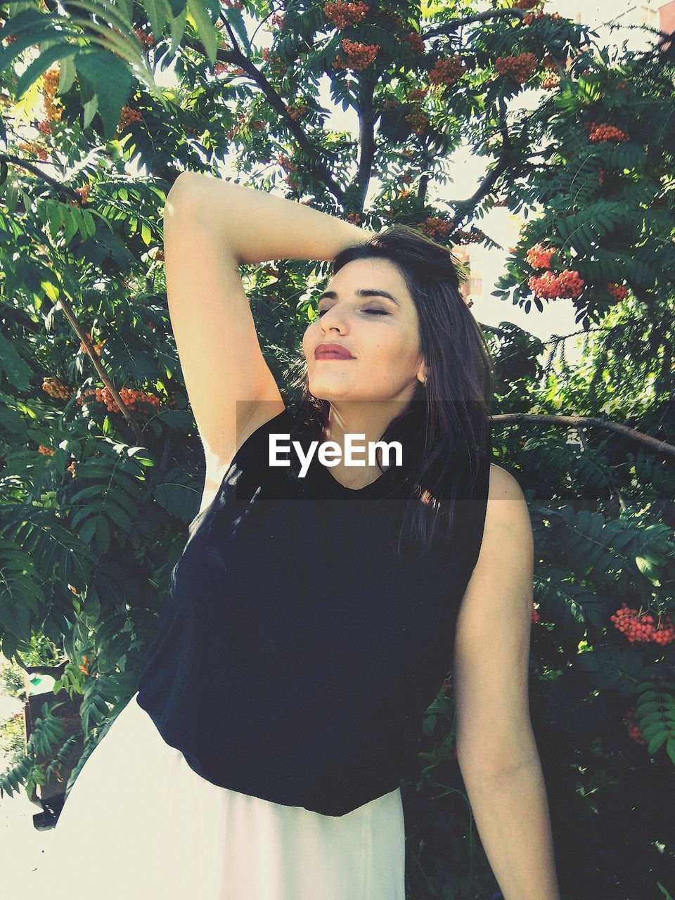 Beautiful young woman standing by tree at park