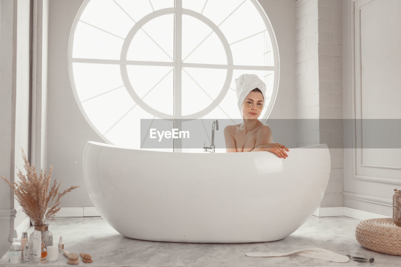 portrait of young woman sitting in bathroom