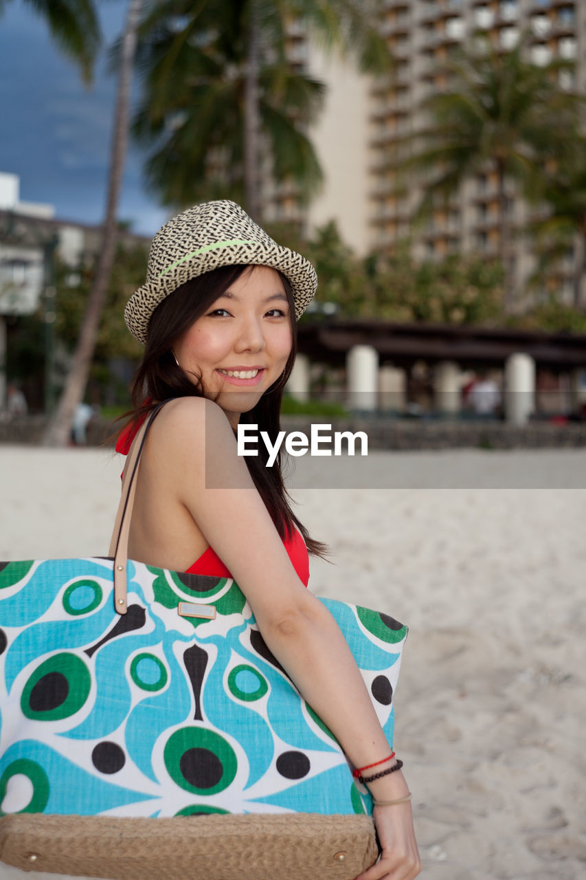 Side view portrait of smiling woman standing at beach