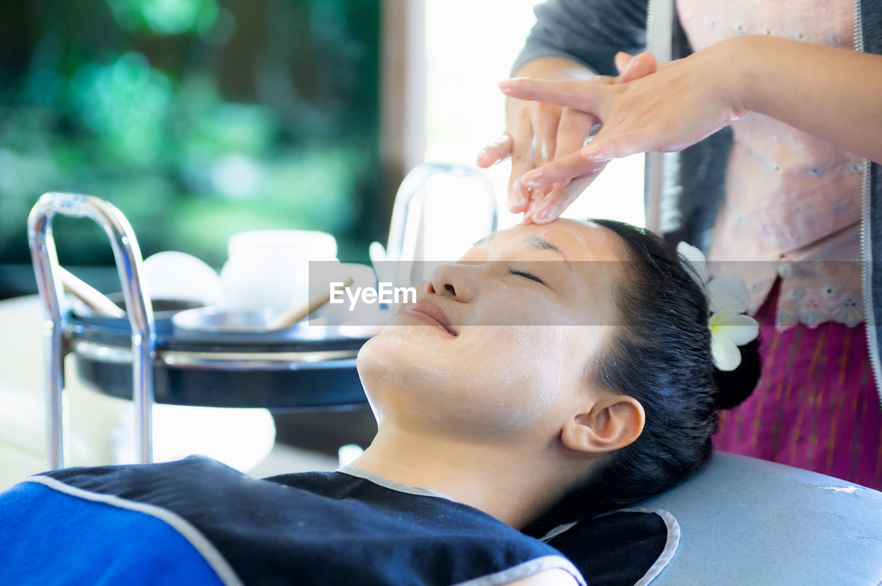 Woman happily lays down for a staff member to wash, massage and scrub her face.