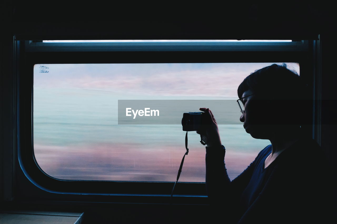 Woman photographing through window in train