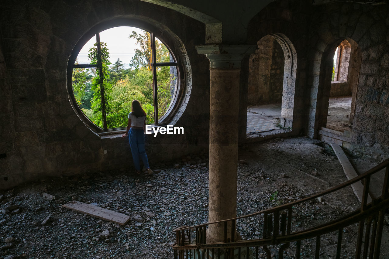 Teen girl standing by the window in an abandoned building