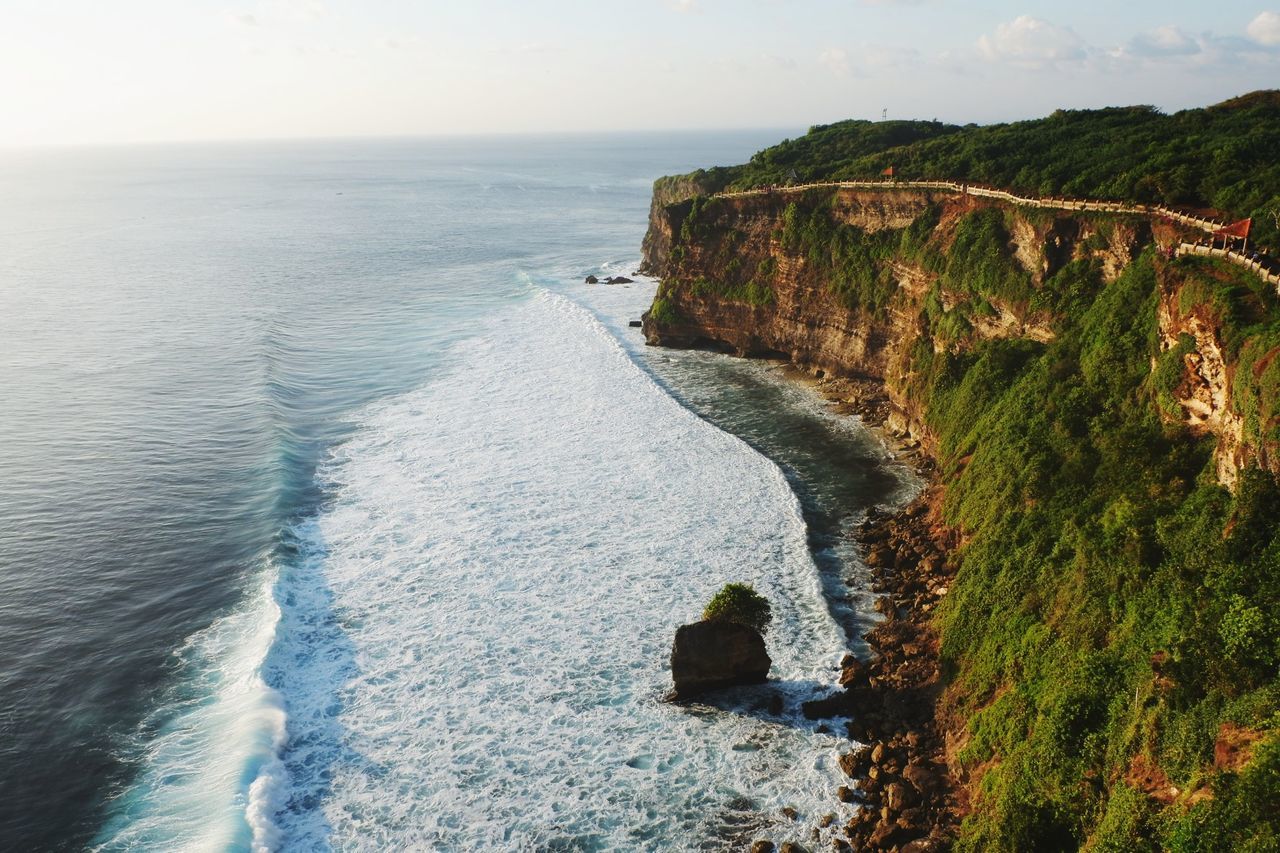 Scenic view of mountain by sea against sky during sunset