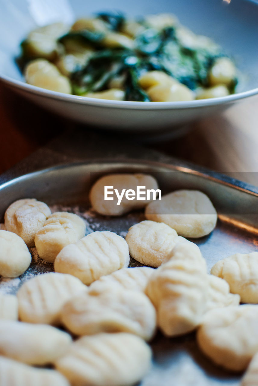 Close-up of pasta dough in tray by seafood in bowl on table