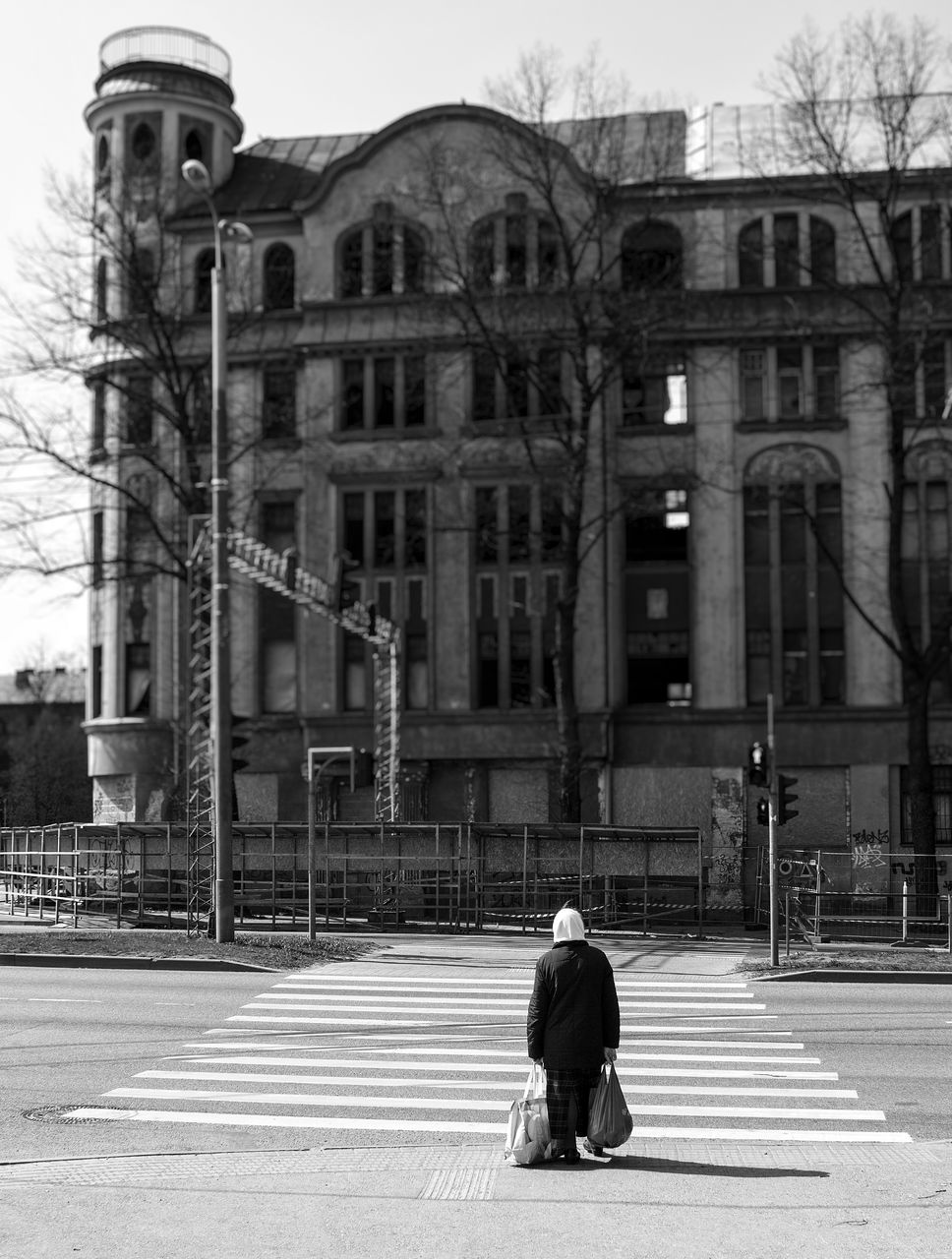 FULL LENGTH REAR VIEW OF MAN WALKING ON STREET AGAINST BUILDINGS