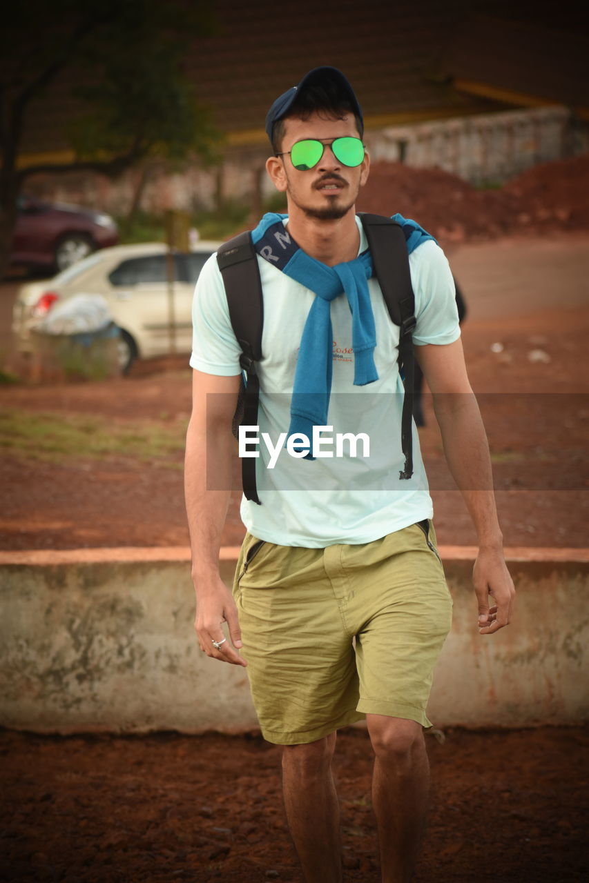 Portrait of young man in sunglasses walking on footpath