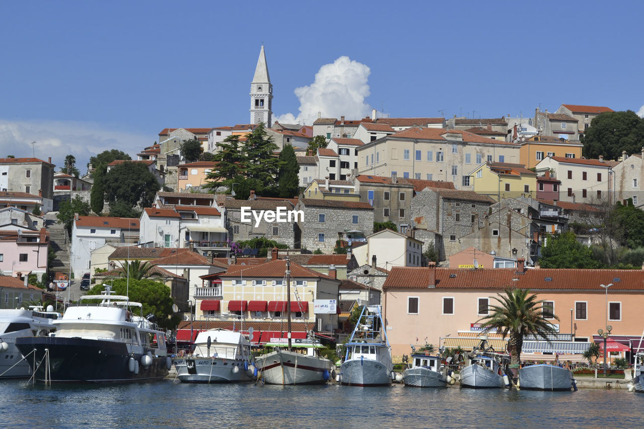 SAILBOATS IN HARBOR BY BUILDINGS AGAINST SKY