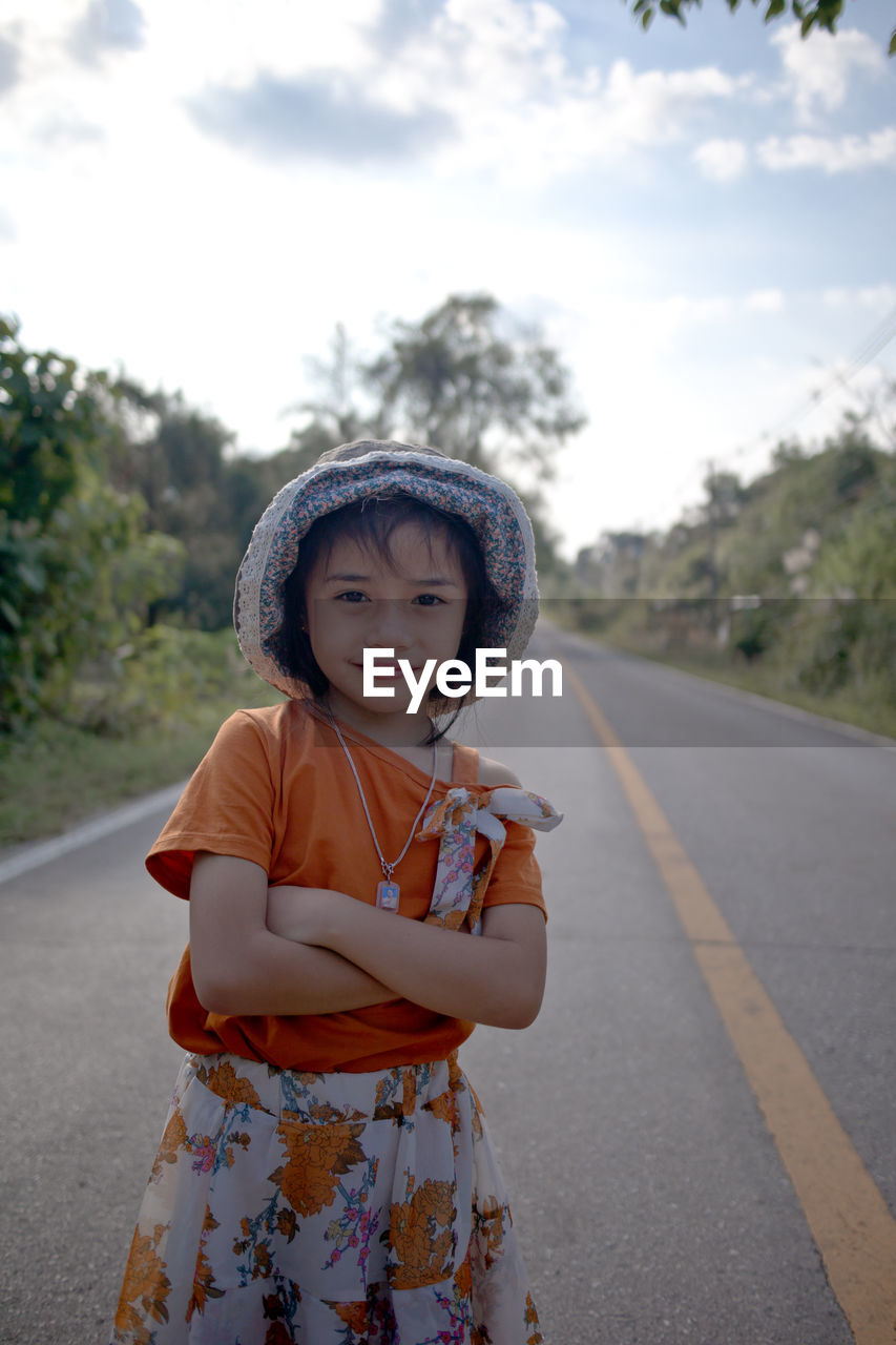 Girl standing on road against sky