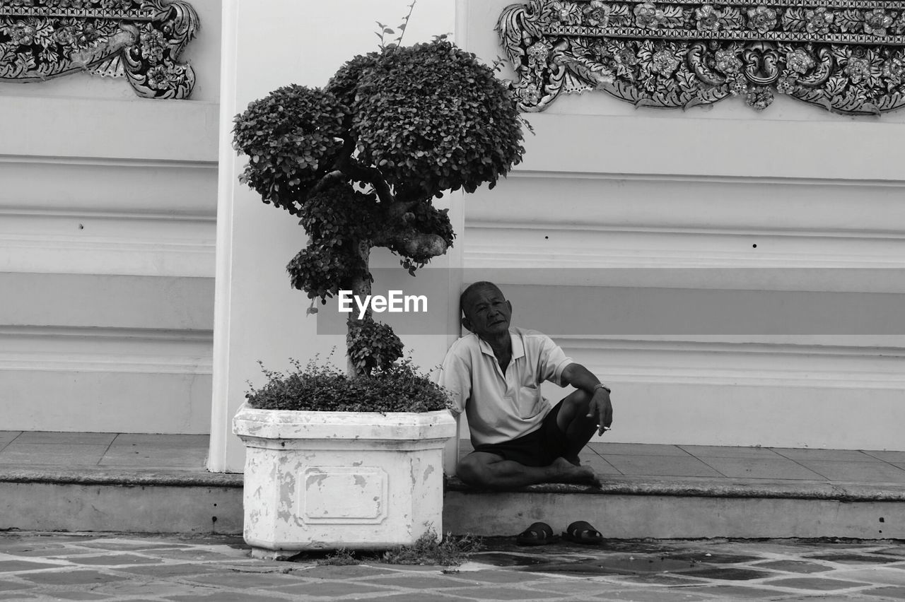 Old homeless man sitting on footpath