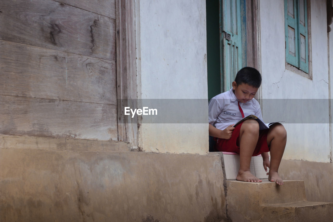 Boy reading book at doorway