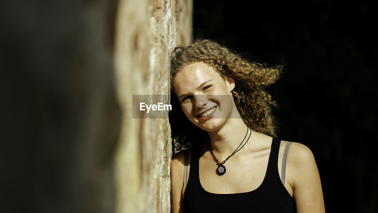 Portrait of happy beautiful woman leaning on wall