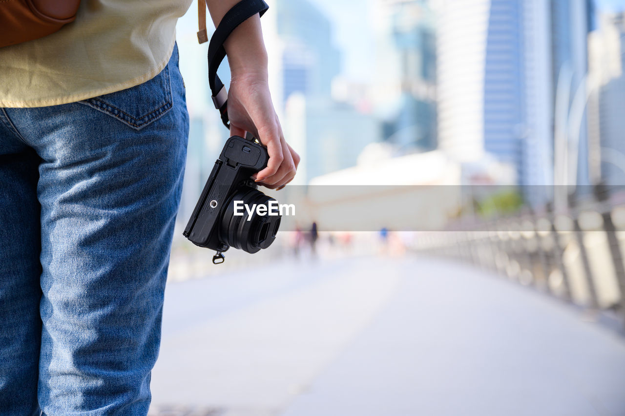 MIDSECTION OF MAN HOLDING CAMERA