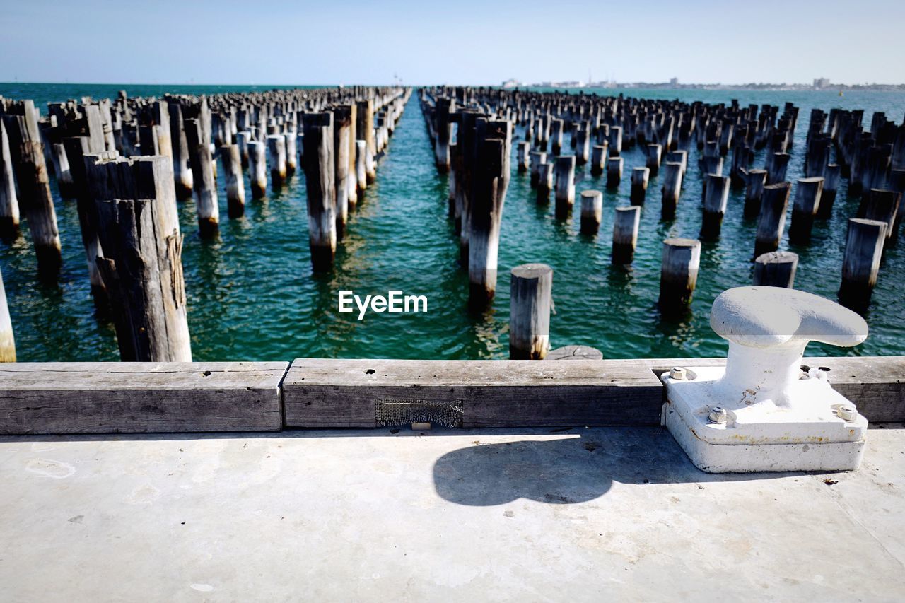 WOODEN POSTS ON PIER AGAINST SKY