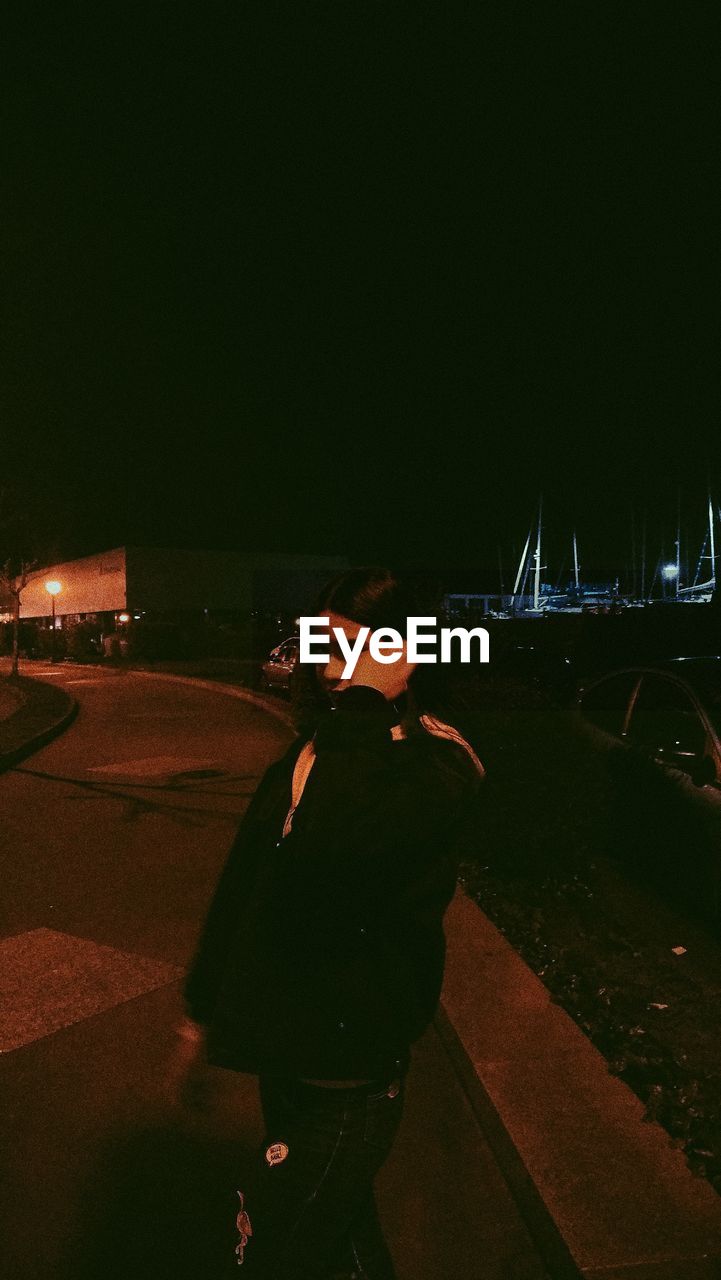 Woman standing on street at night