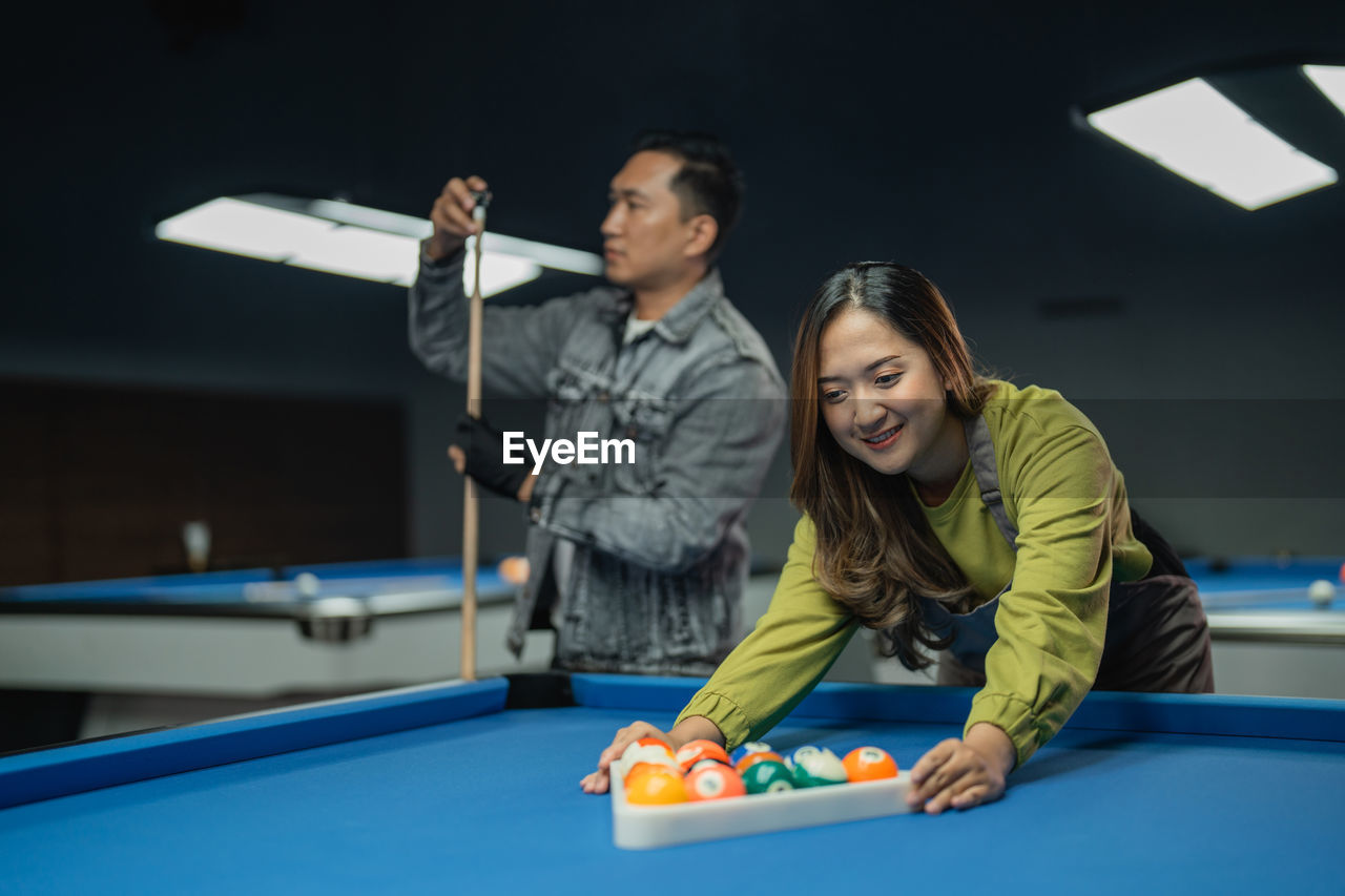 portrait of smiling young woman playing pool