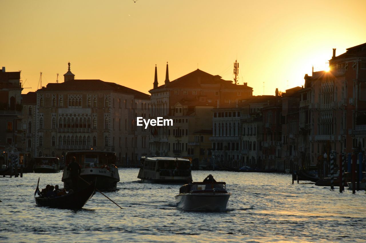 Boats on grand canal by buildings against sky during sunset in city