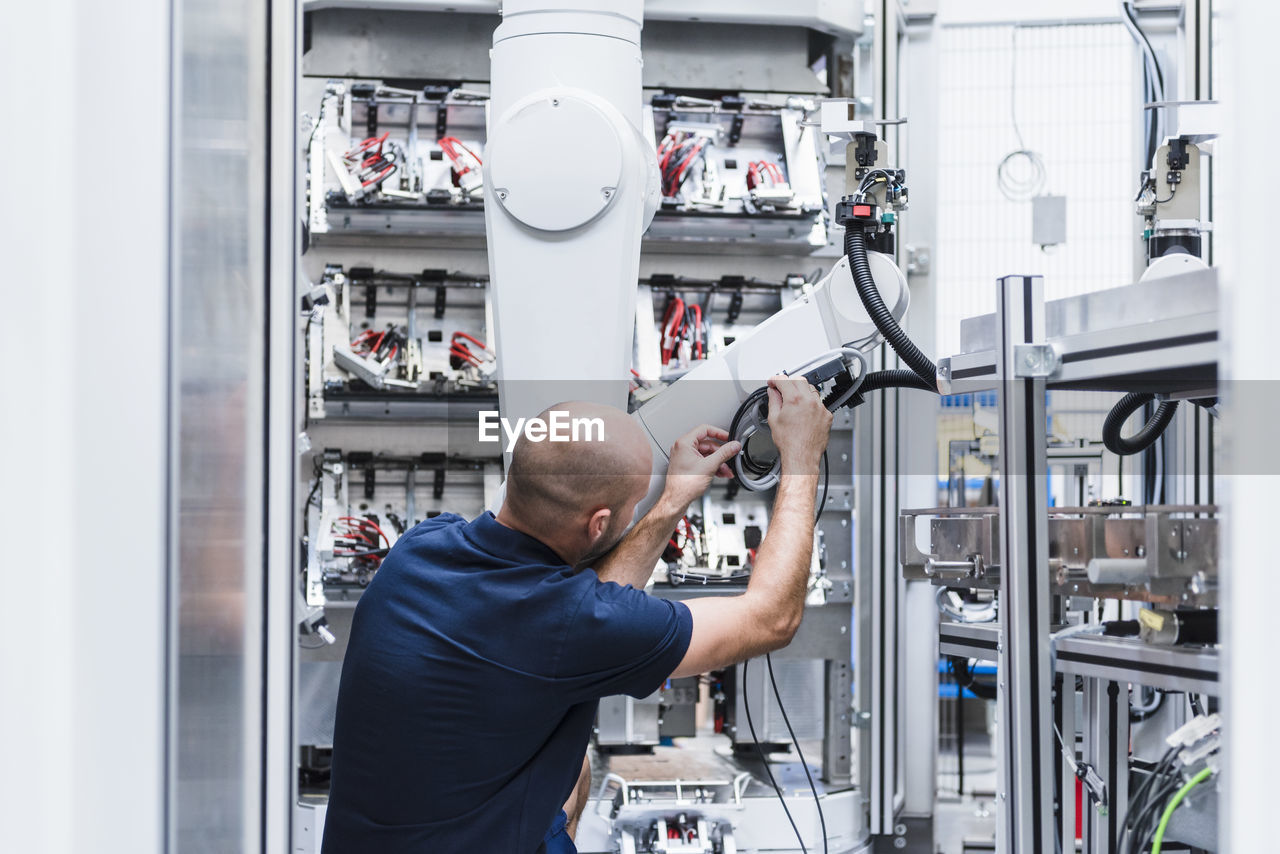 Man working at industrial robot in modern factory