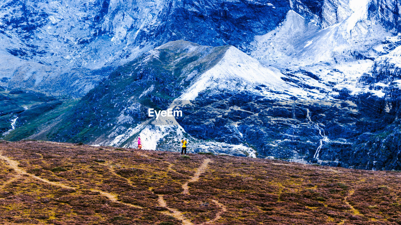 People on field against mountain during winter