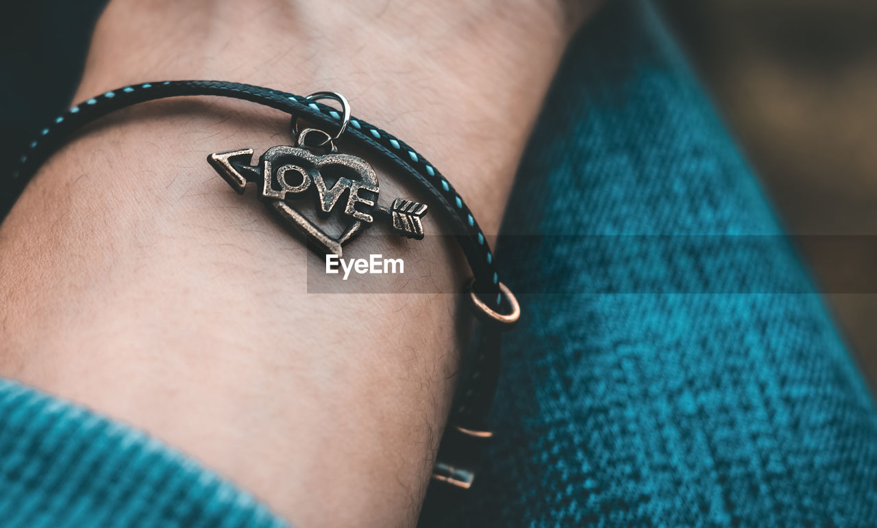 Close-up of person wearing bracelet with love text
