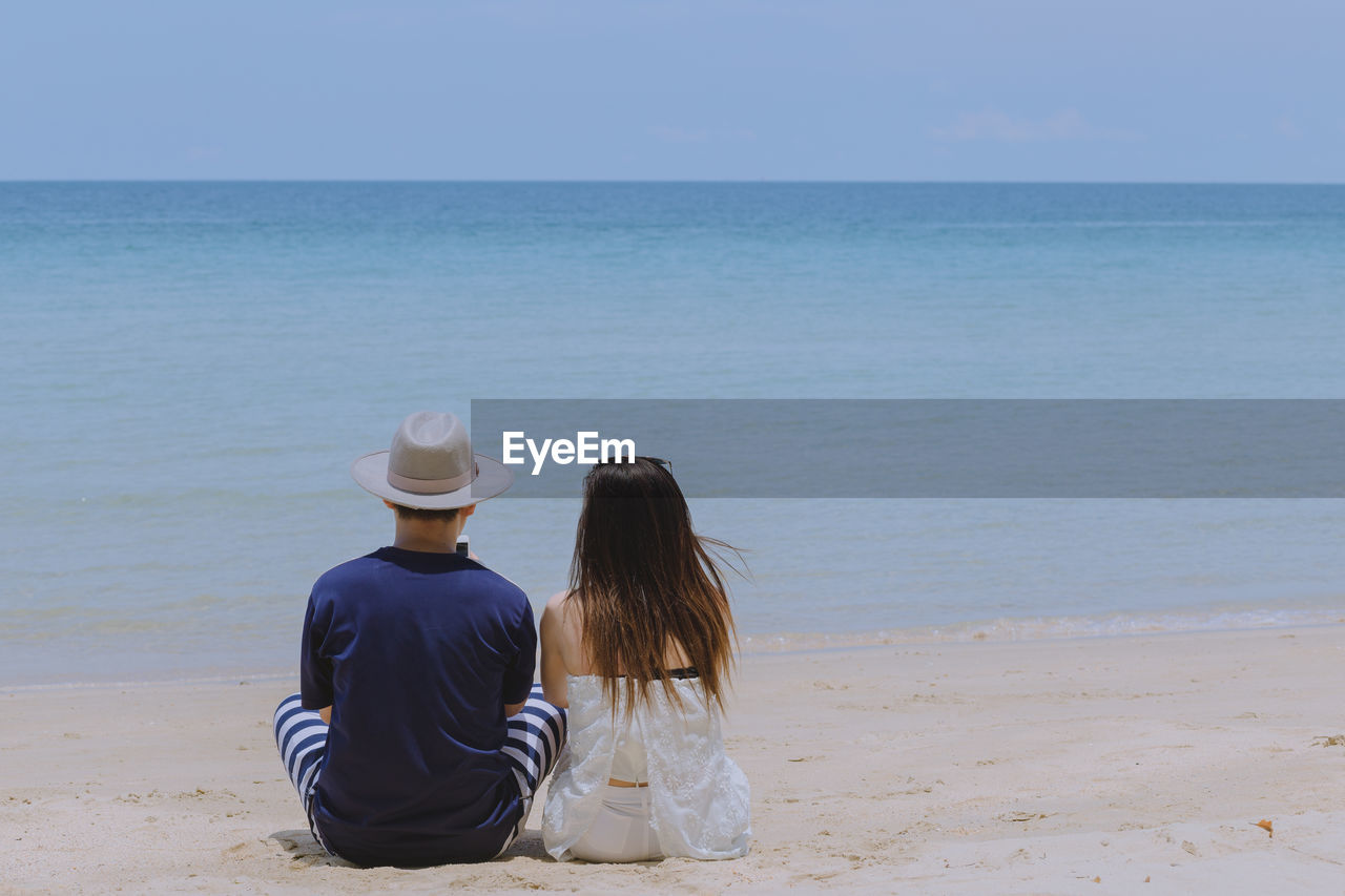 Rear view of couple sitting at beach