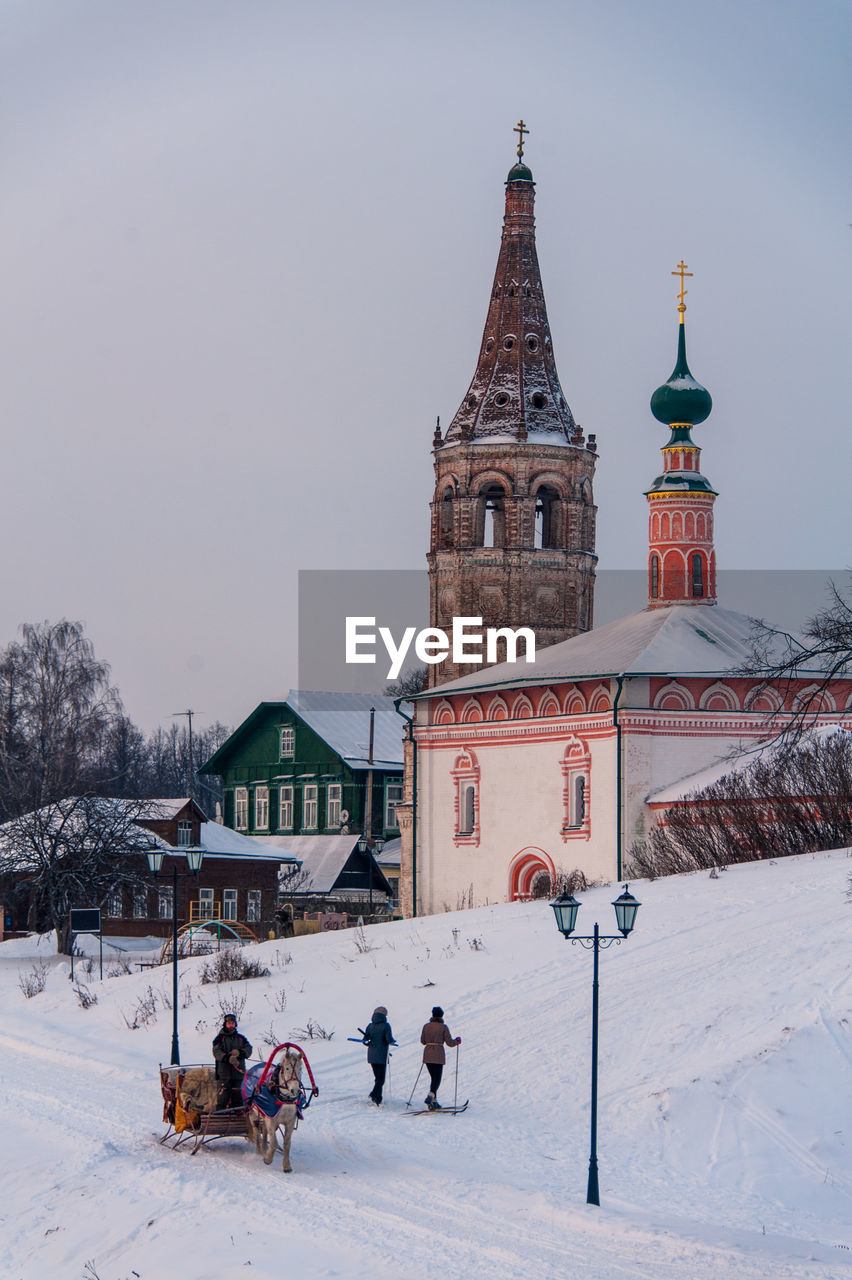 People on snow field against historic church