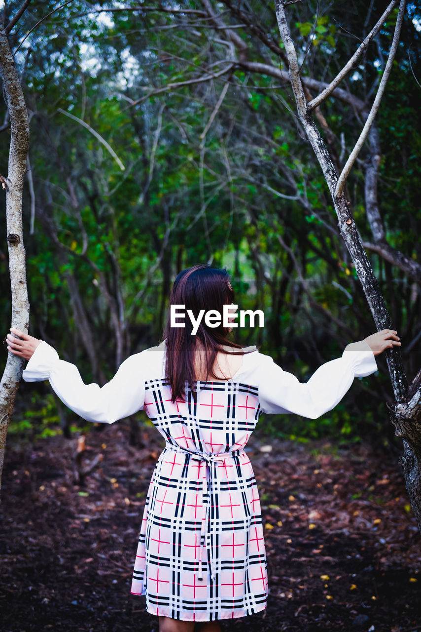 WOMAN STANDING AGAINST TREES