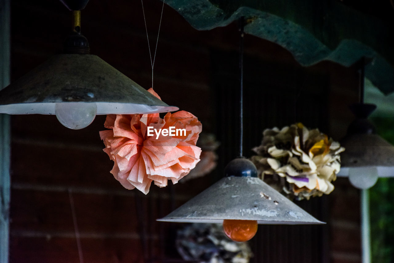 Paper flowers hanging by pendant lights in abandoned room