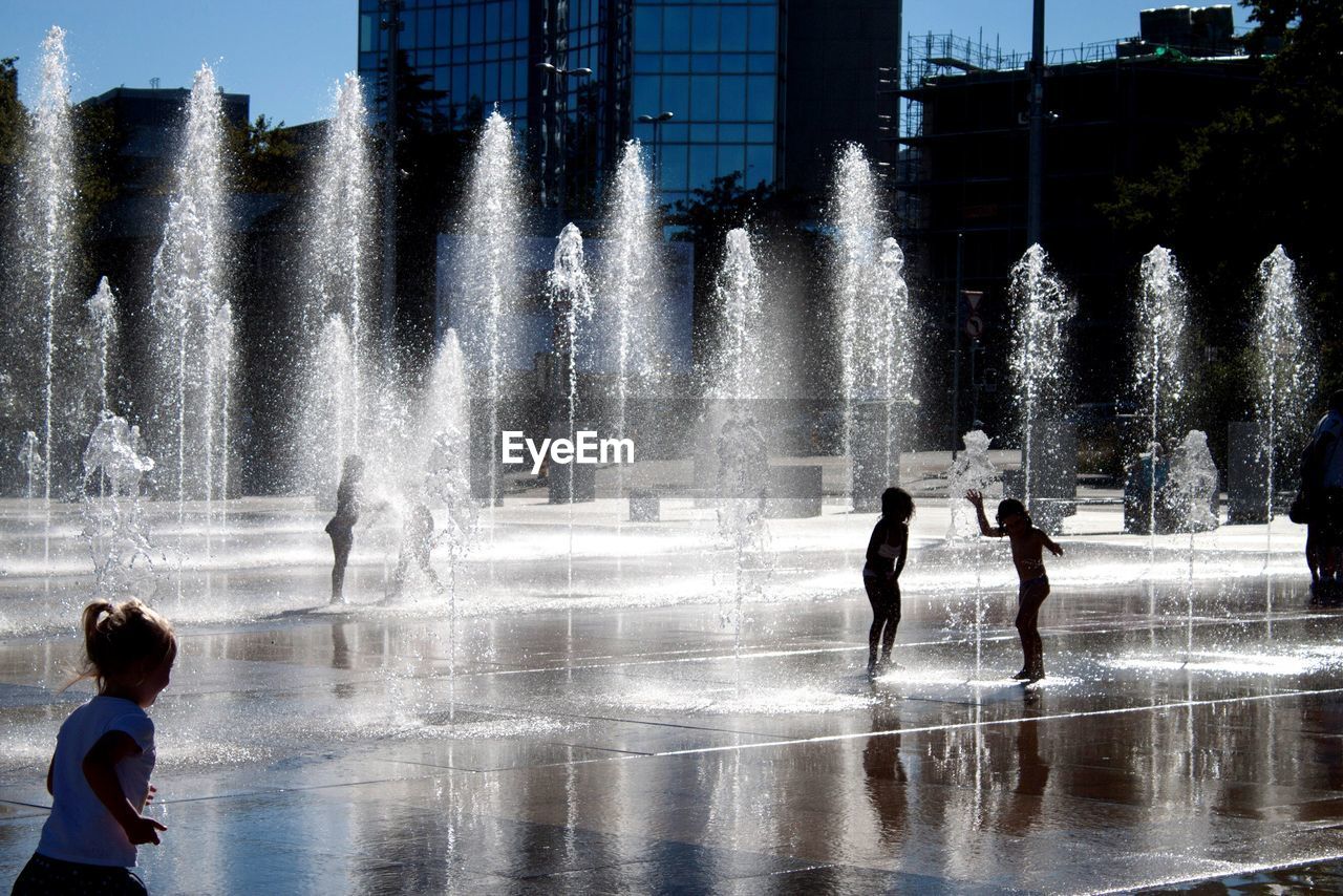 PEOPLE ENJOYING AT FOUNTAIN AGAINST BLURRED BACKGROUND