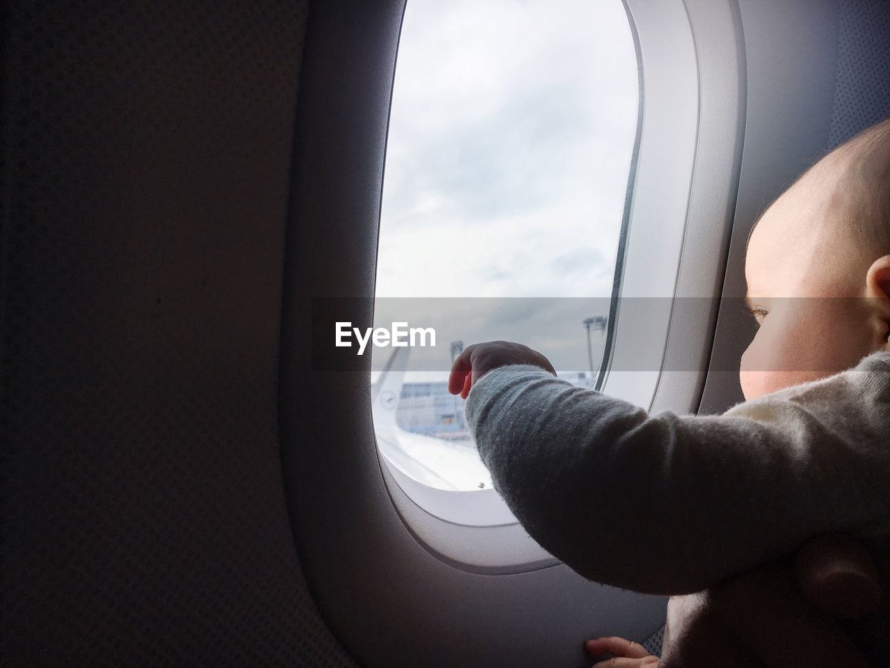 Close-up of child looking towards airplane window