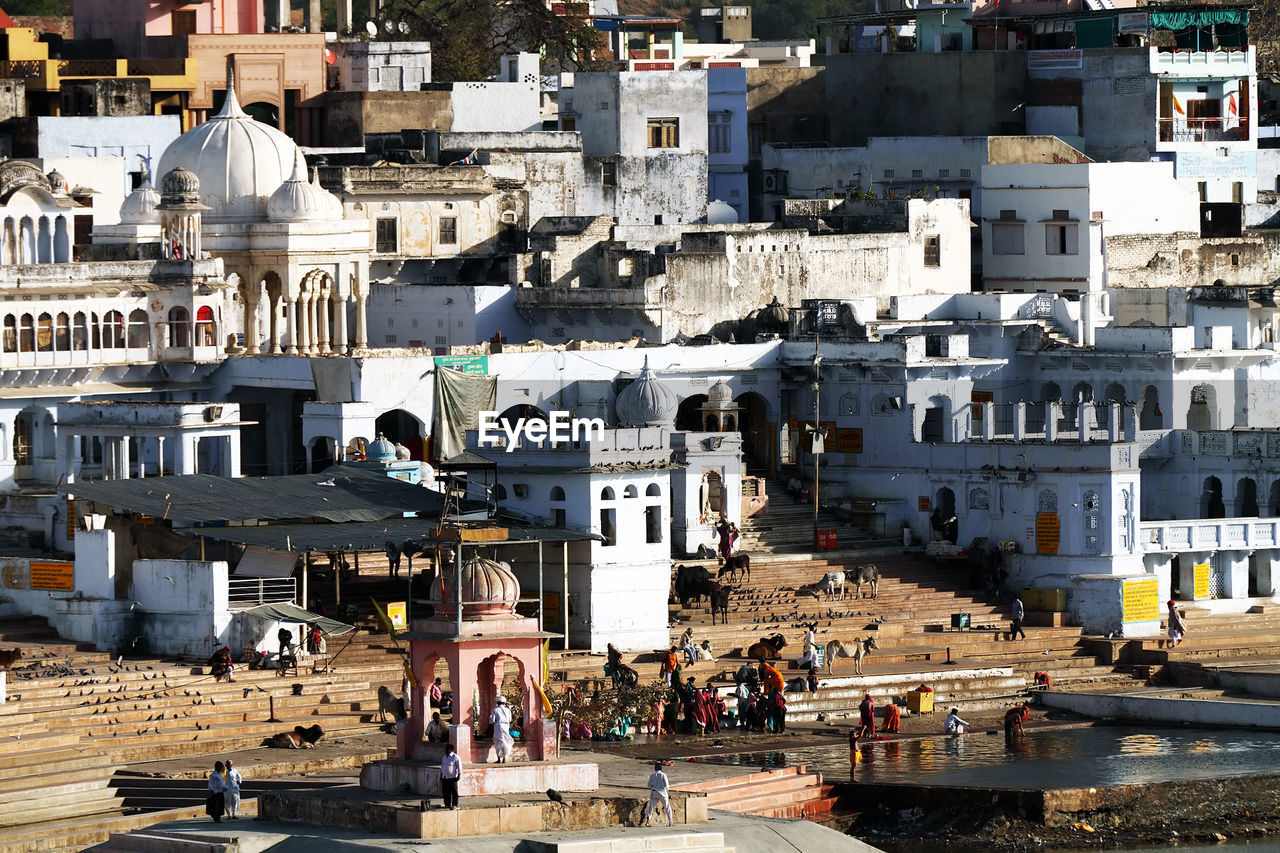 High angle view of people at temple by lake and white buildings