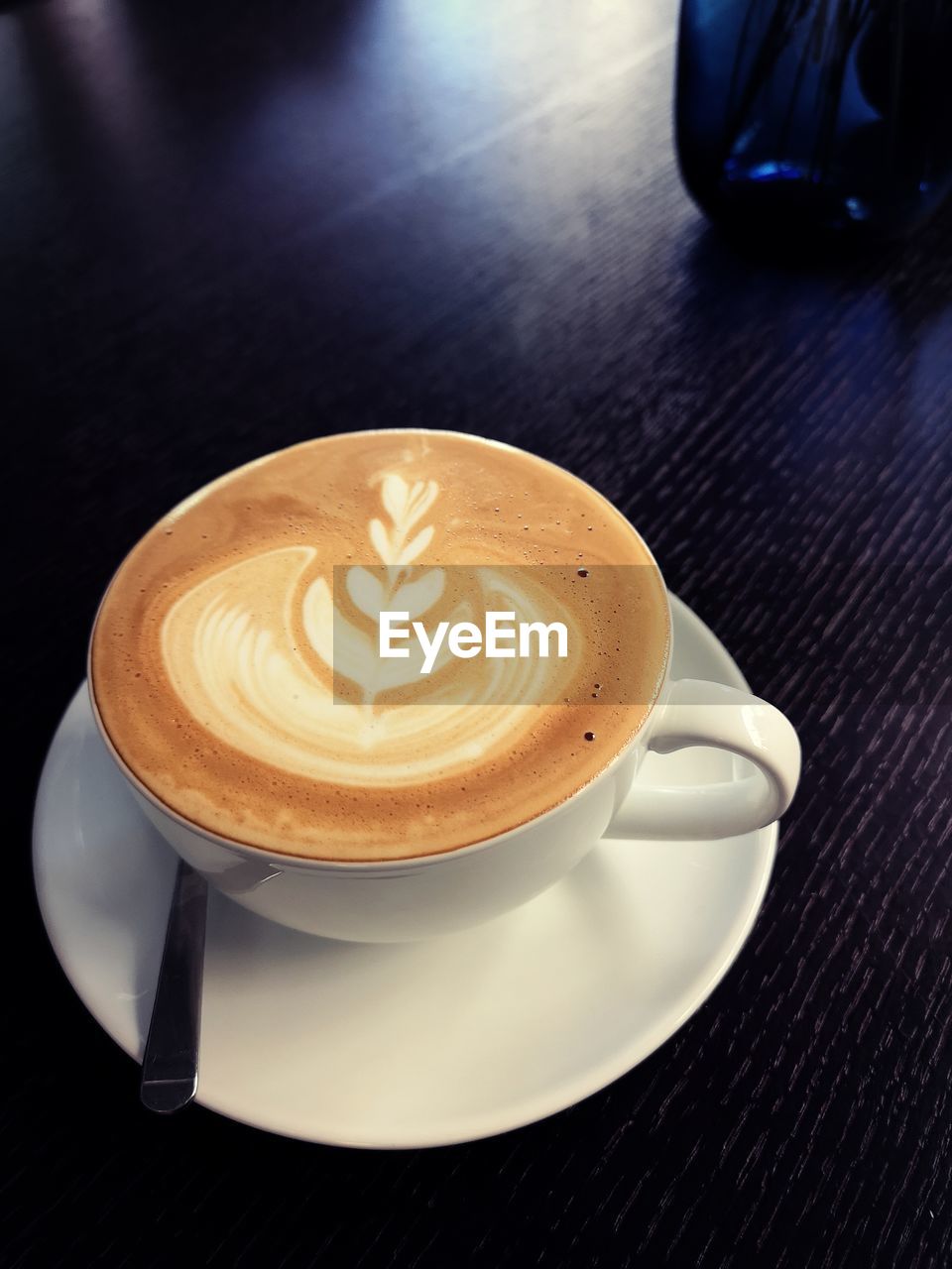 High angle view of a hot cappuccino cup on dark blue table