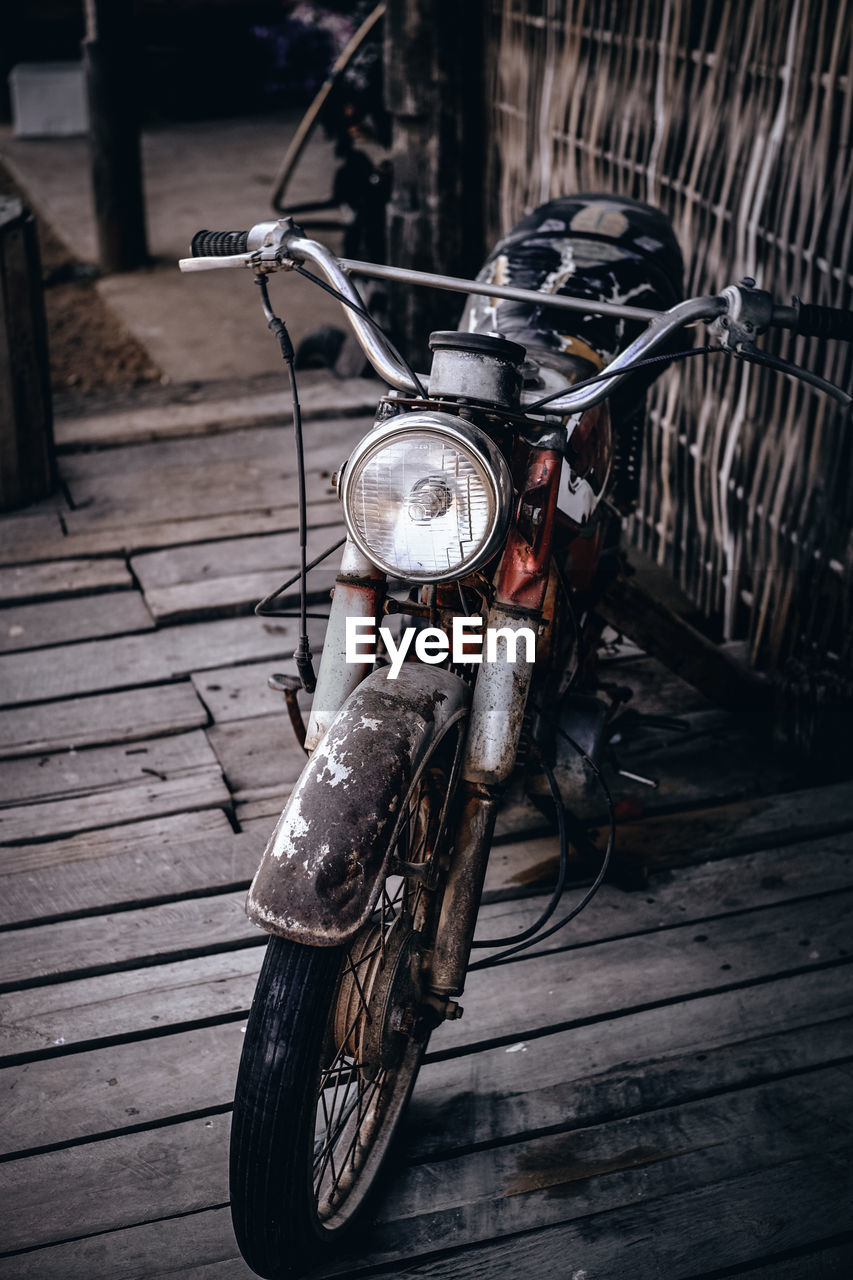 CLOSE-UP OF BICYCLE PARKED ON WOODEN FOOTPATH