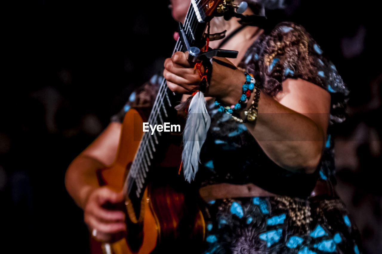 Midsection of female musician playing guitar during concert