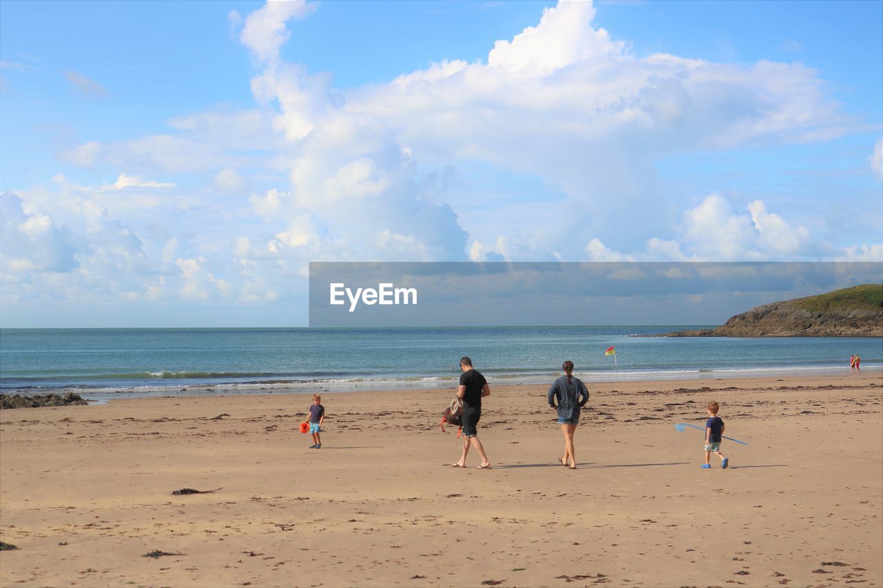 Family walking at beach against sky