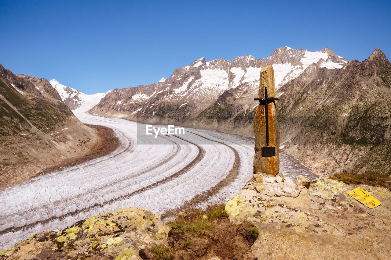 Road leading towards mountains against clear blue sky