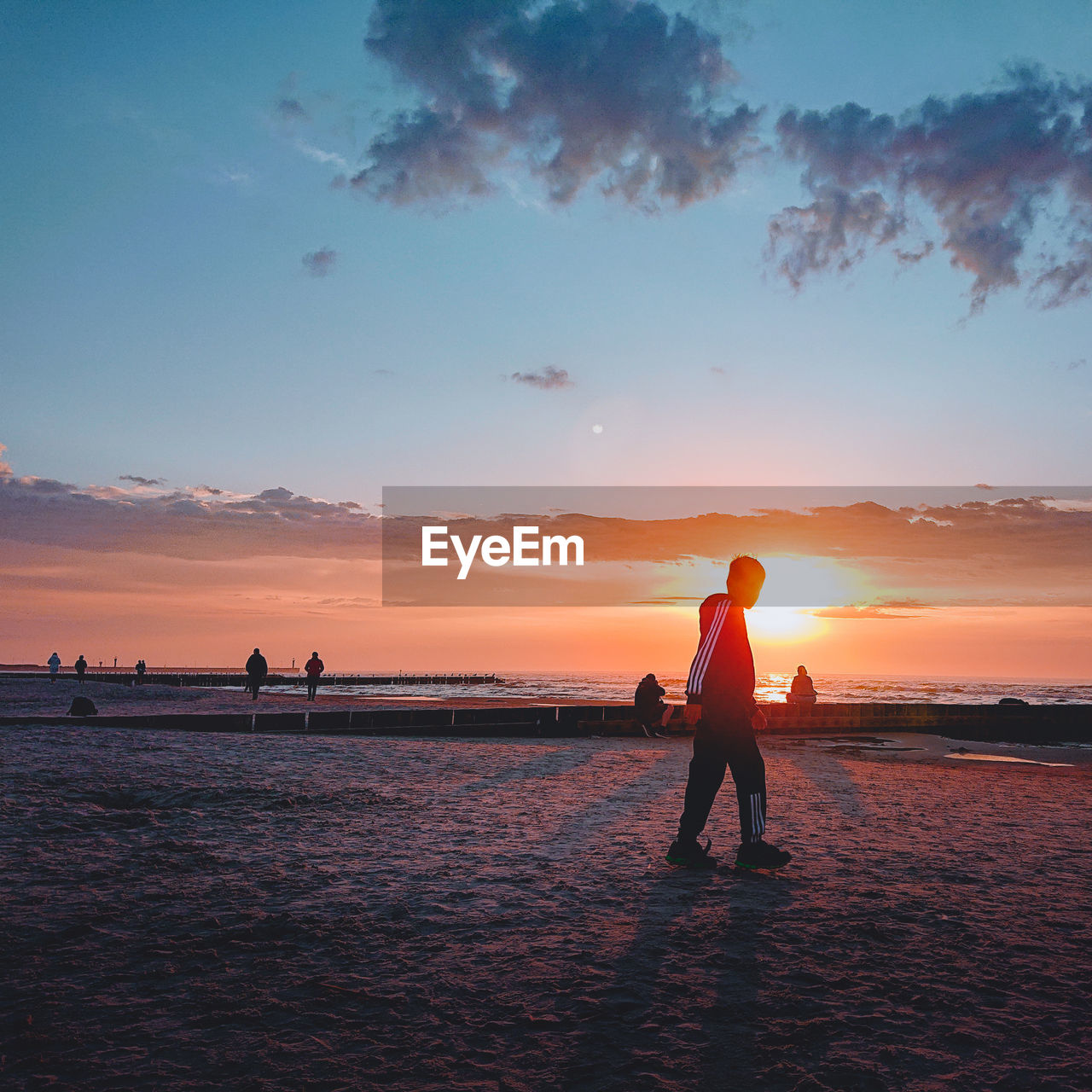 SILHOUETTE WOMEN STANDING ON BEACH AGAINST SKY DURING SUNSET