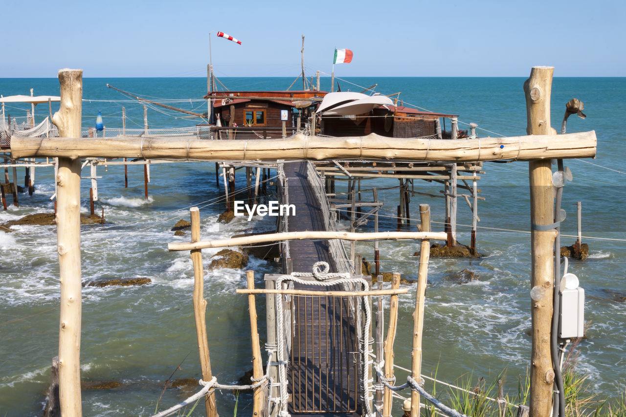 WOODEN POST IN SEA AGAINST SKY