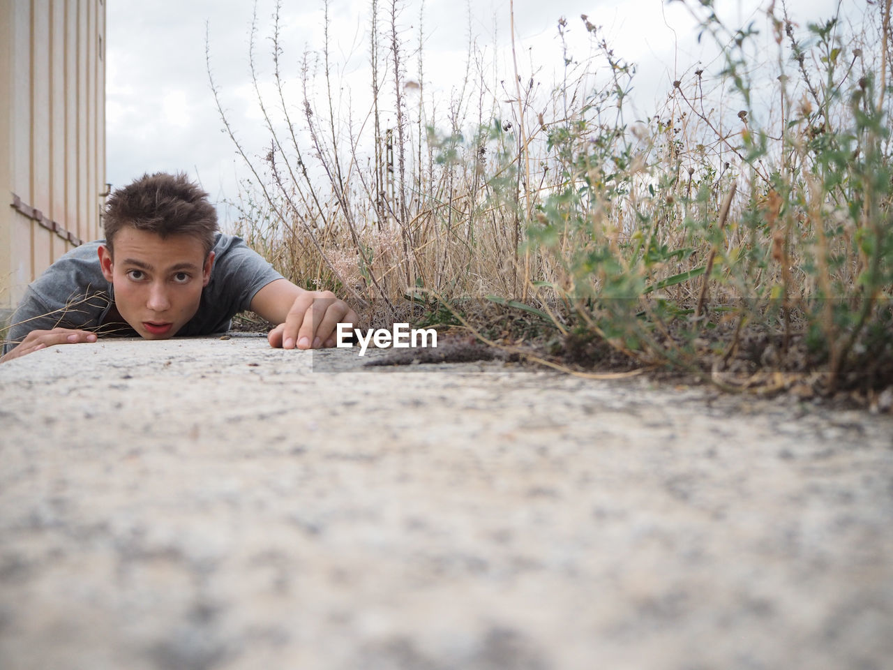 Portrait of young man lying on footpath