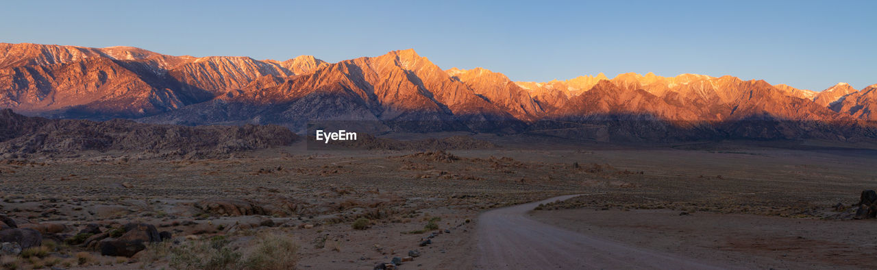 Panorama of movie road in alabama hills leading into the sierra nevadas lit by brilliant morning sun