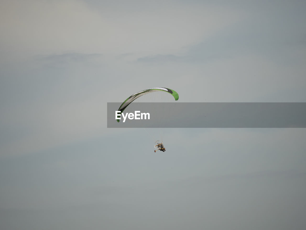 Low angle view of enjoying person powered parachute against sky