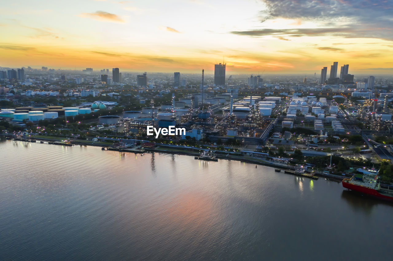 HIGH ANGLE VIEW OF RIVER AMIDST BUILDINGS AGAINST SKY DURING SUNSET