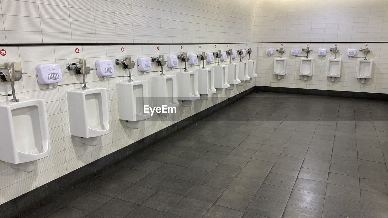 in a row, bathroom, urinal, indoors, hygiene, tile, public restroom, flooring, public building, room, floor, plumbing fixture, interior design, order, sink, no people, repetition, architecture