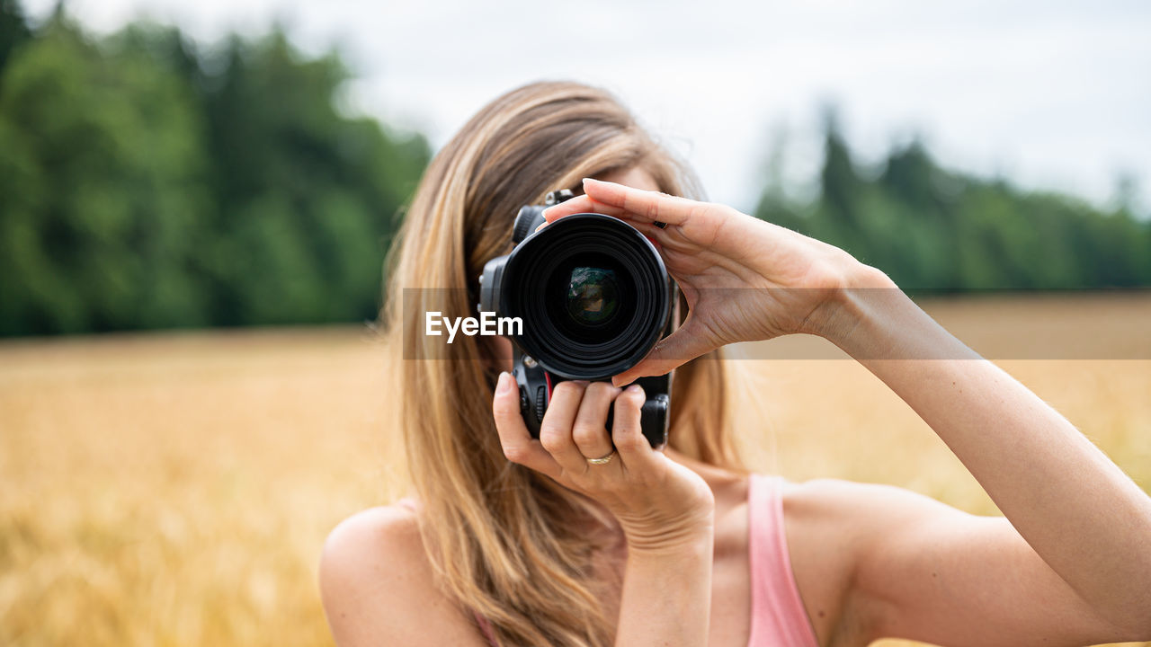 PORTRAIT OF WOMAN PHOTOGRAPHING AGAINST CAMERA